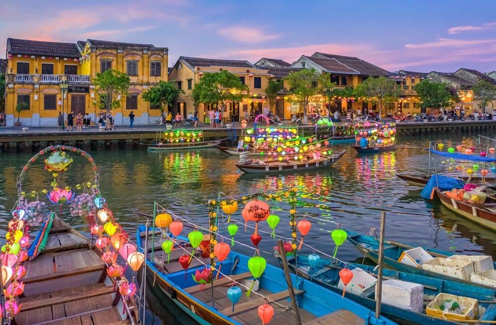 barche nel fiume di Hoi An circondate da lanterne e edifici coloniali gialli